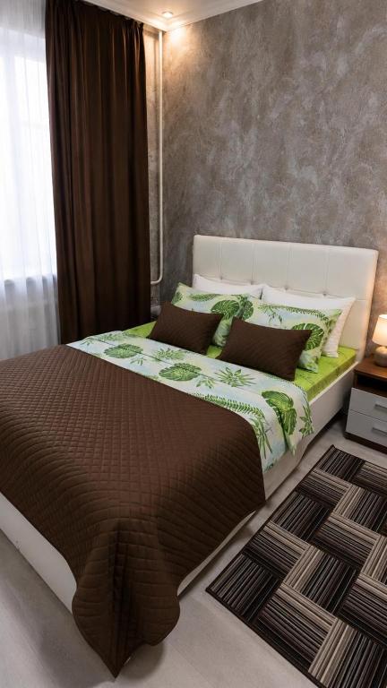 a bedroom with a large bed with brown and green sheets at Машхур Жусупа 25 in Pavlodar