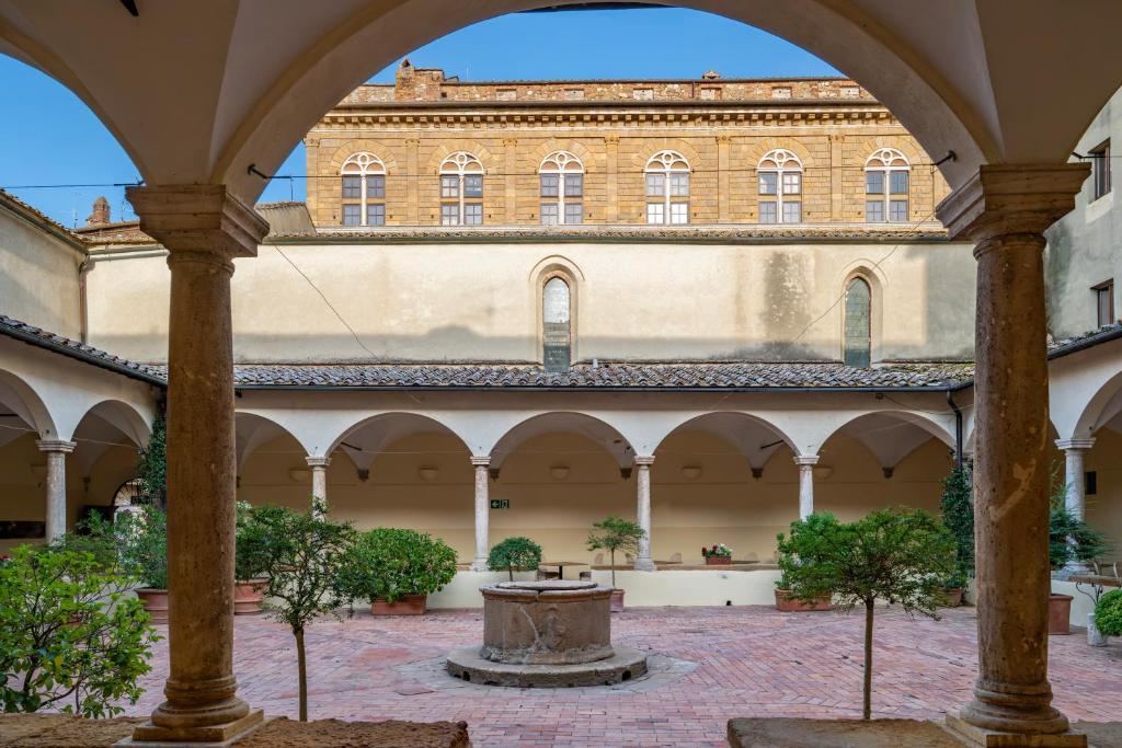 a courtyard with a fountain in the middle of a building at Relais Cloister Pienza in Pienza