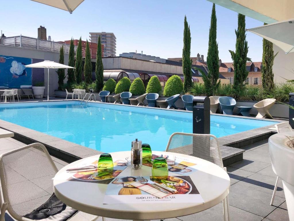 a table and chairs next to a swimming pool at Novotel Metz Centre in Metz