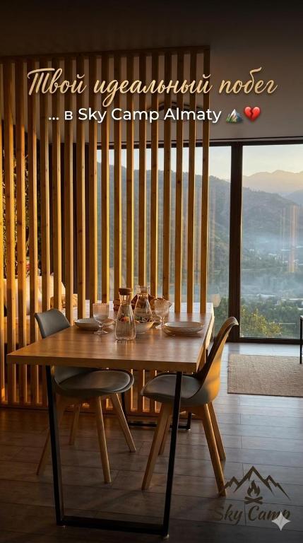 a wooden table and chairs in a room with a window at SkyCamp Almaty in Almaty