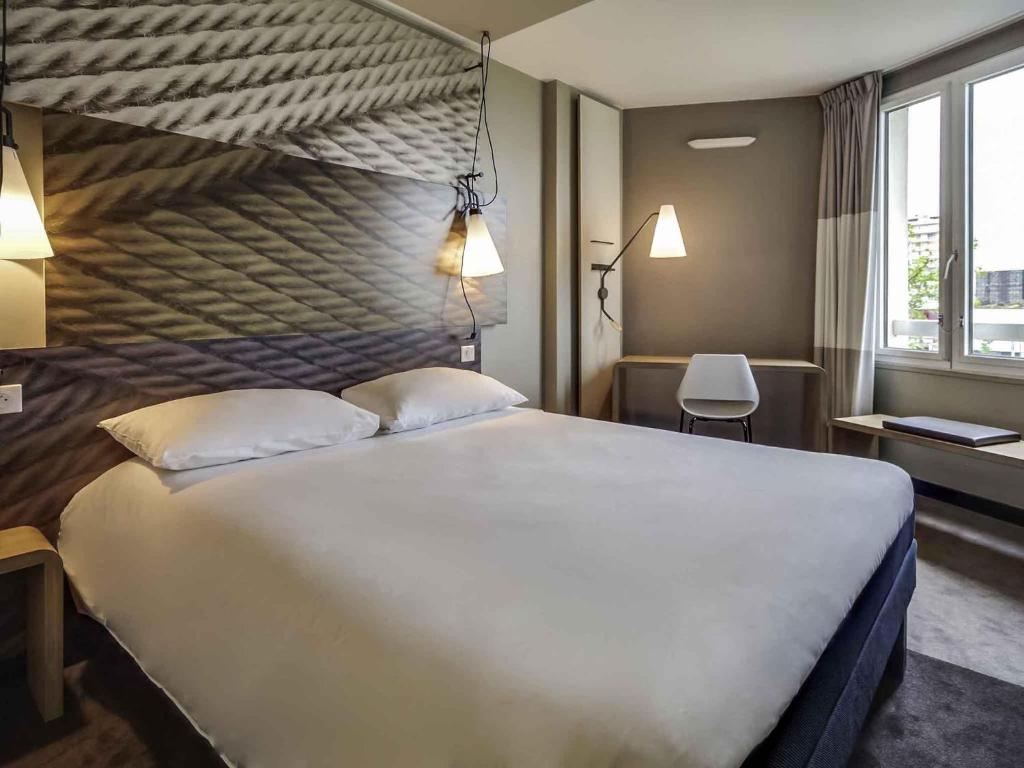 a bedroom with a large white bed with two pillows at ibis Orleans Centre Gare in Orléans