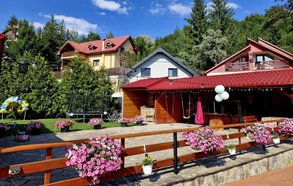 a wooden bench in front of a house with flowers at Casa Delia in Slănic-Moldova