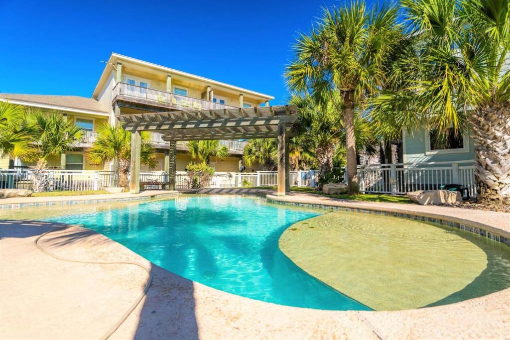 a swimming pool in front of a house with palm trees at After Dune Delight in Port Aransas