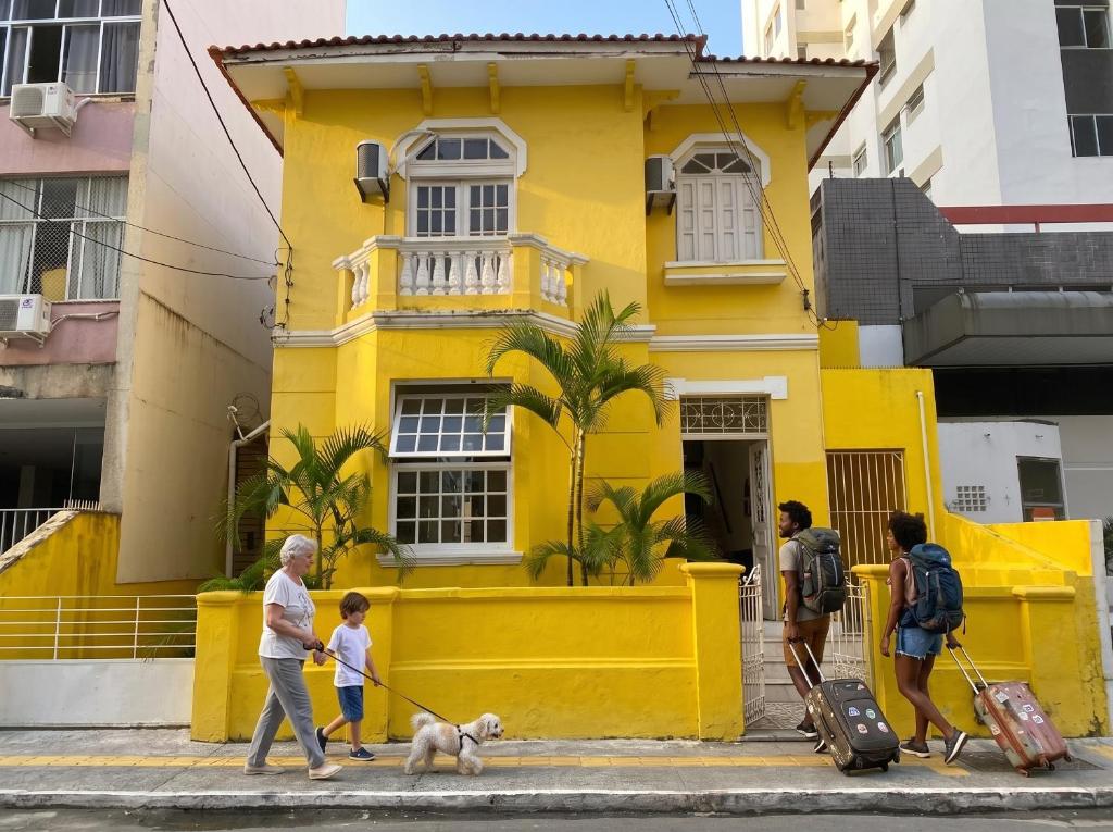a group of people walking a dog in front of a yellow building at Odara Hostel & Guesthouse in Salvador
