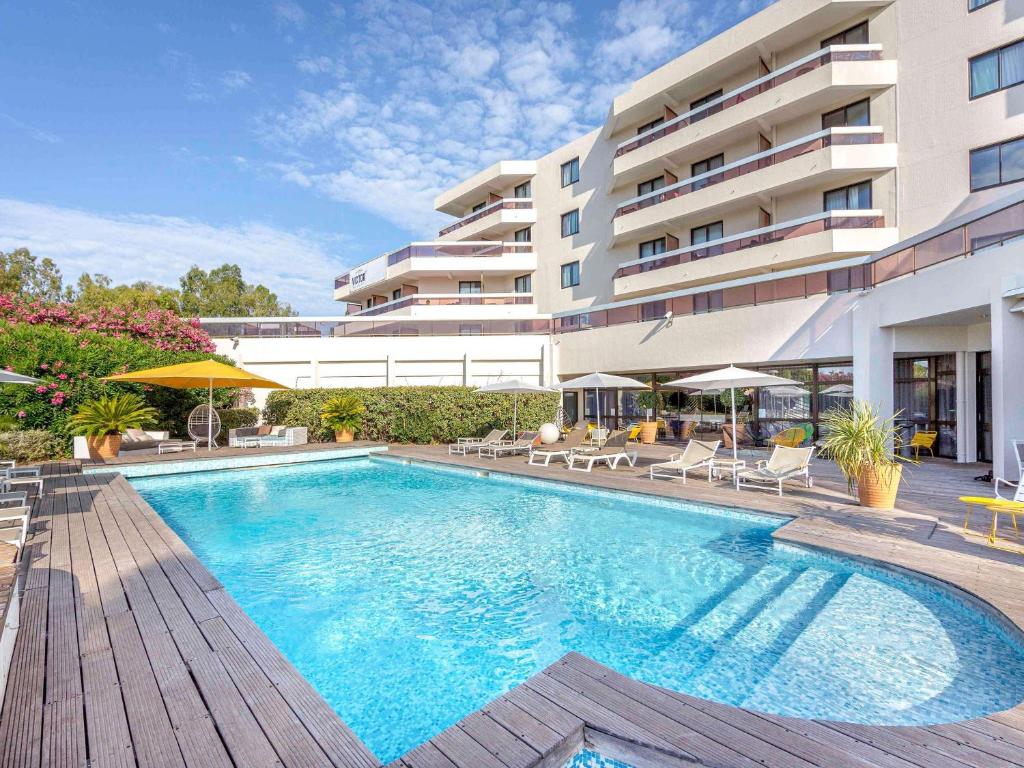 a swimming pool in front of a building at Mercure Hyères Centre Côte d'Azur in Hyères