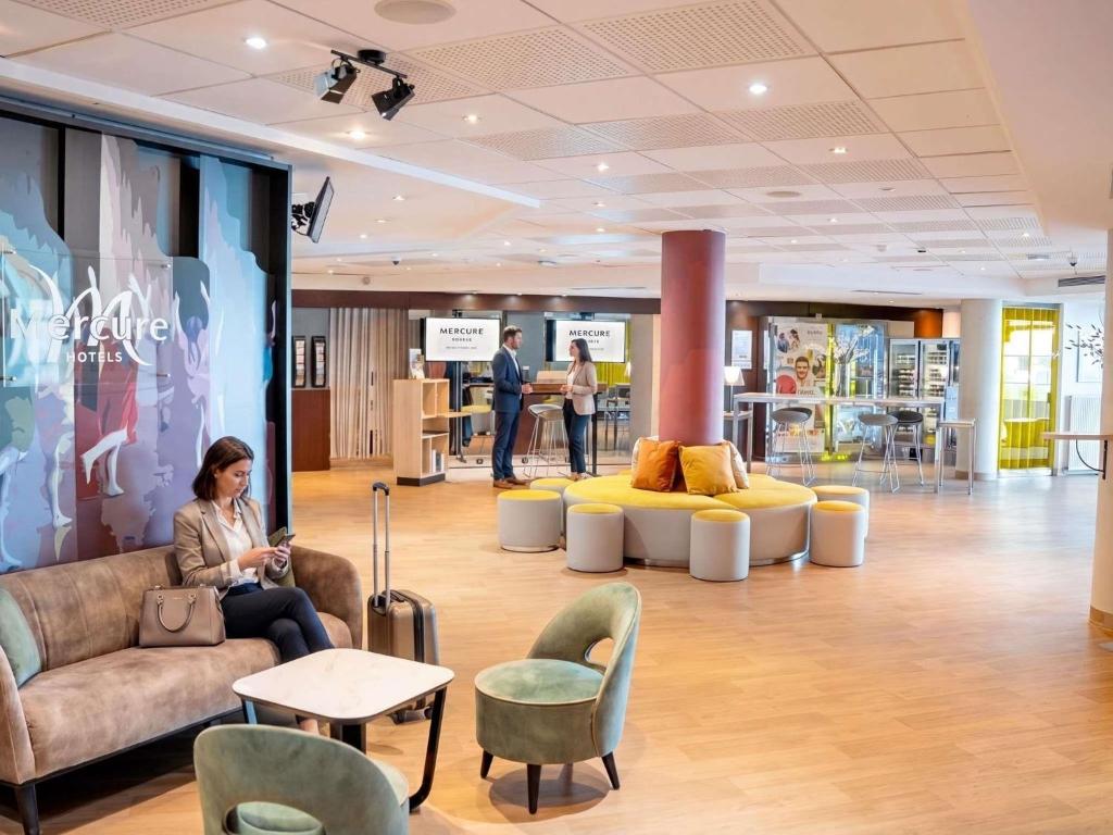 a woman sitting on a couch in the lobby of a store at Mercure Paris Massy Gare TGV in Massy