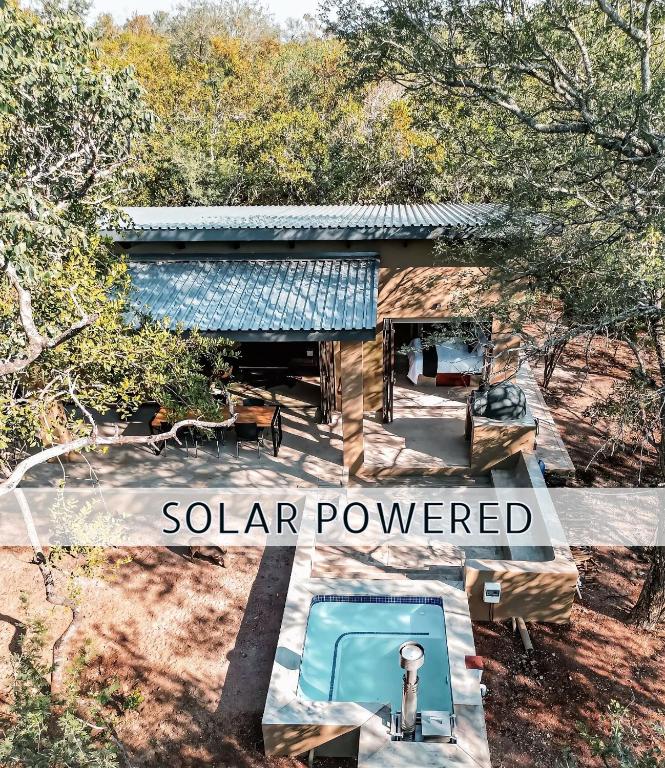 a swimming pool in front of a solar powered house at Shongololo Bush Villa in Marloth Park