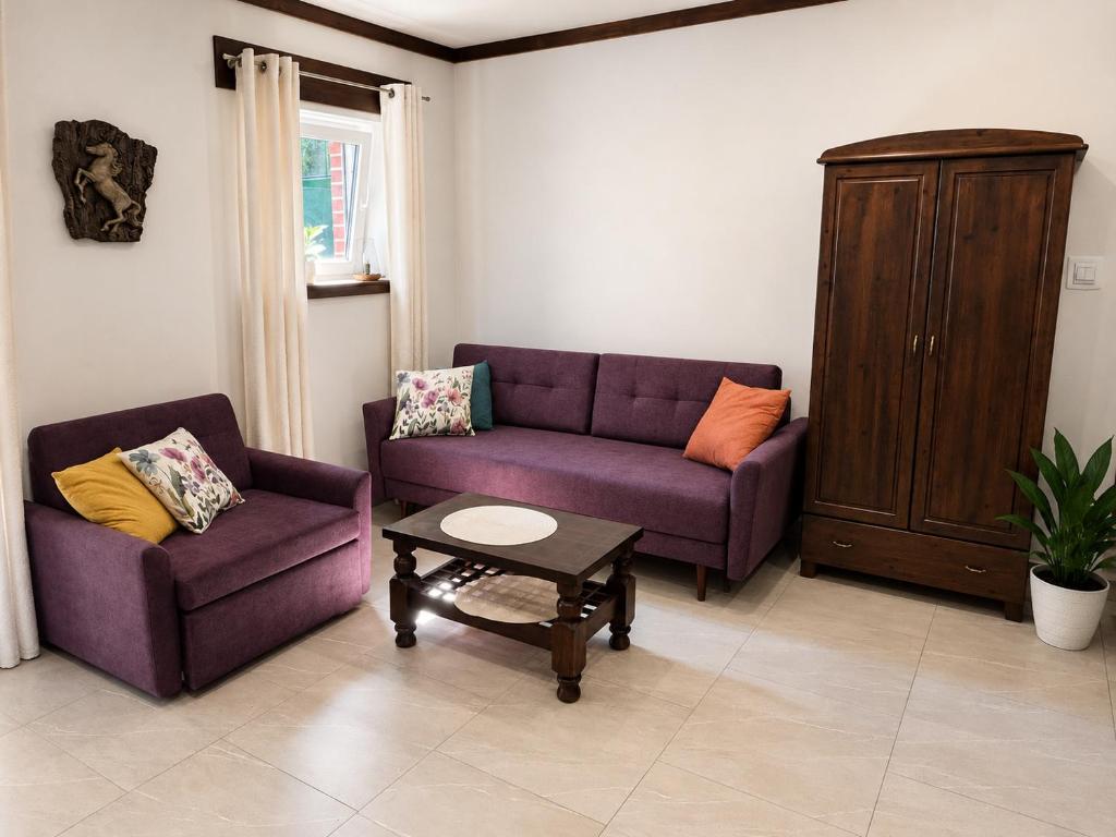a living room with two purple couches and a coffee table at Pokój dyrektora stadniny in Niezgoda