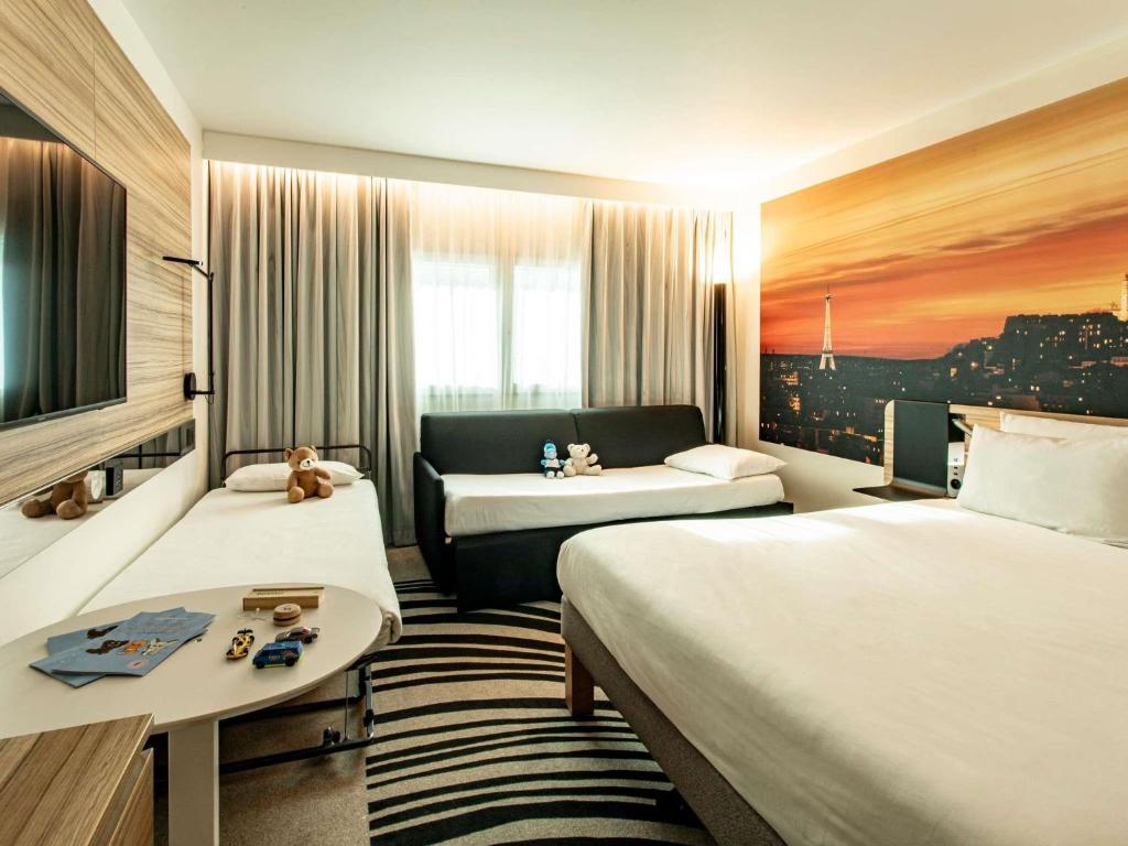 a hotel room with two beds and a couch at Novotel Paris 14 Porte d'Orléans in Paris