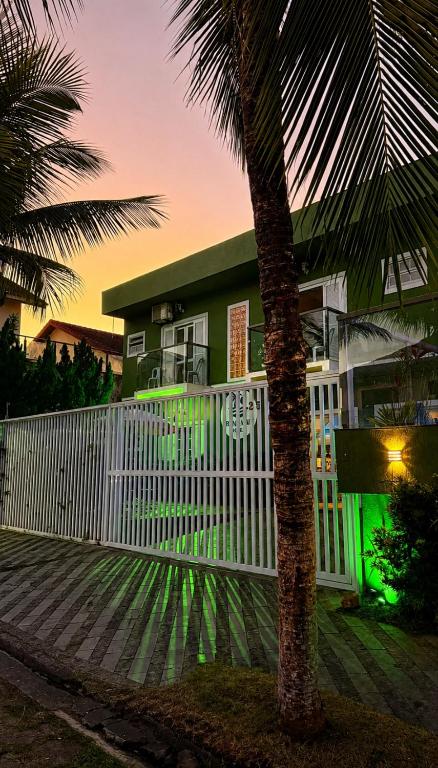 a white fence in front of a house with a palm tree at GrandMaré Hotel in Peruíbe