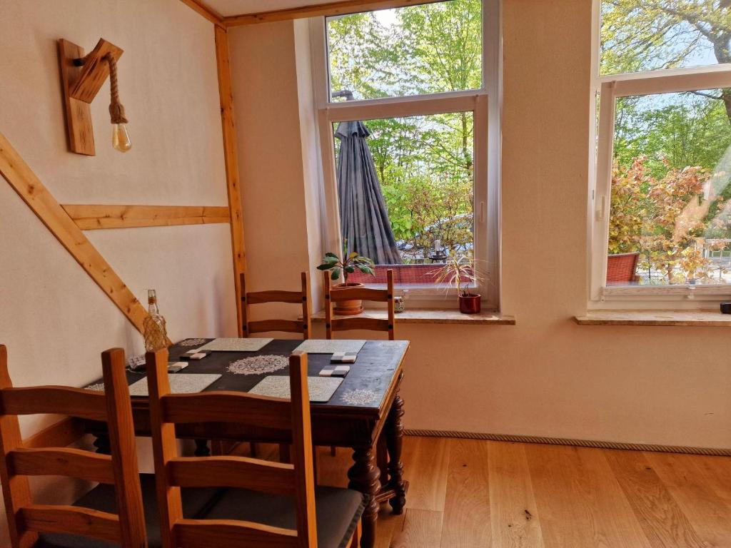 a dining room with a table and two windows at Klanggarten - Yoga, Wald, Stadtrand in Lübeck