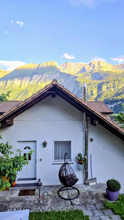 a white house with a wicker chair in front of it at Big 3-bedroom flat with new kitchen in Brienz