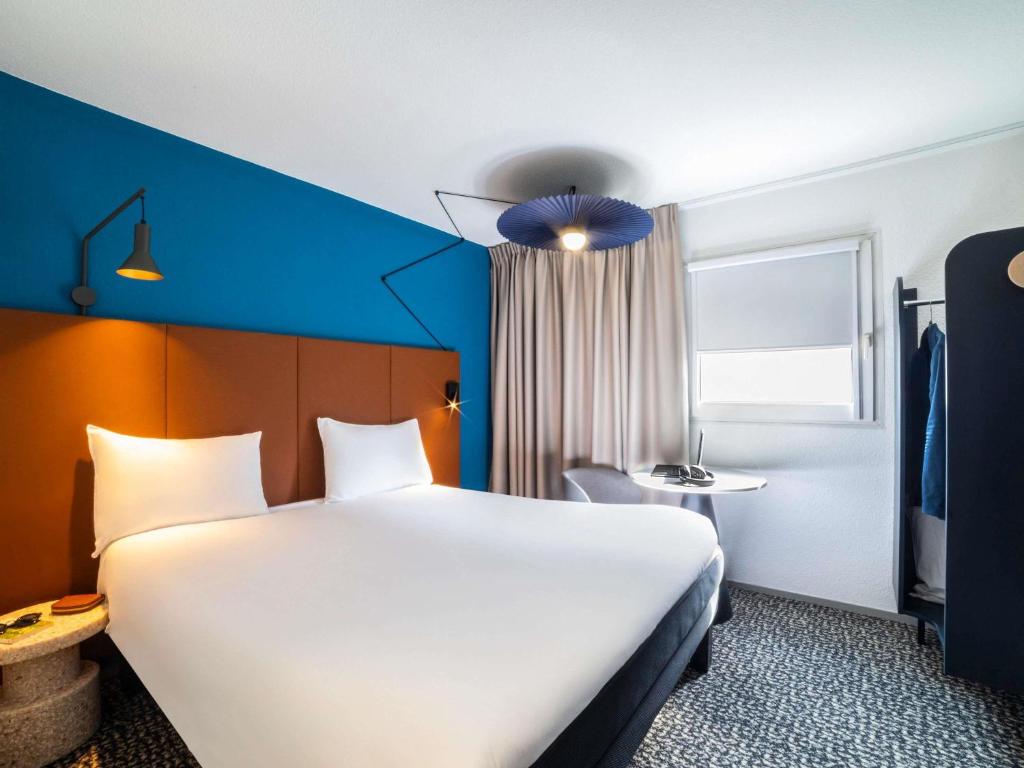 a hotel room with a large bed and a blue wall at ibis Paris porte de Bercy in Charenton-le-Pont