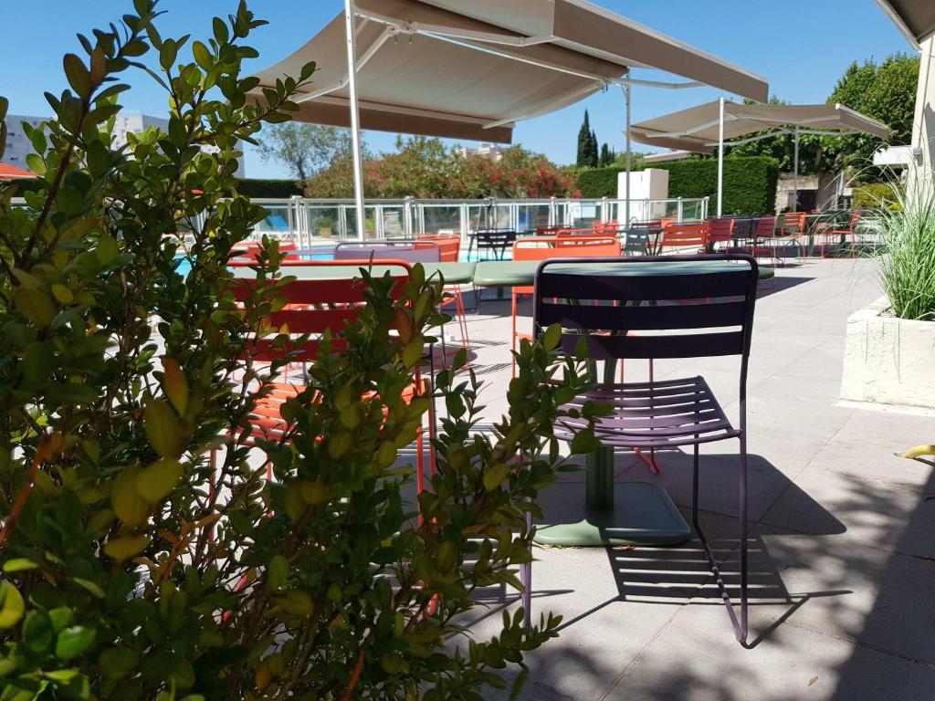 a patio with two chairs and a table and benches at ibis Styles Arles Palais des Congrès in Arles