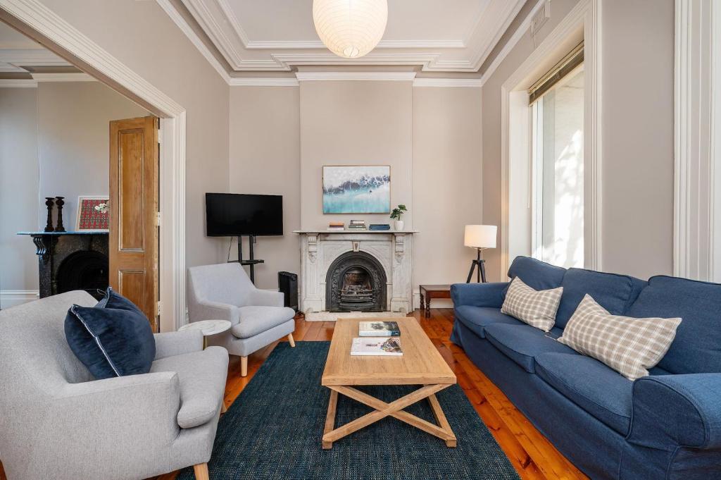 a living room with blue couches and a fireplace at Saint Francis in Fitzroy in Melbourne