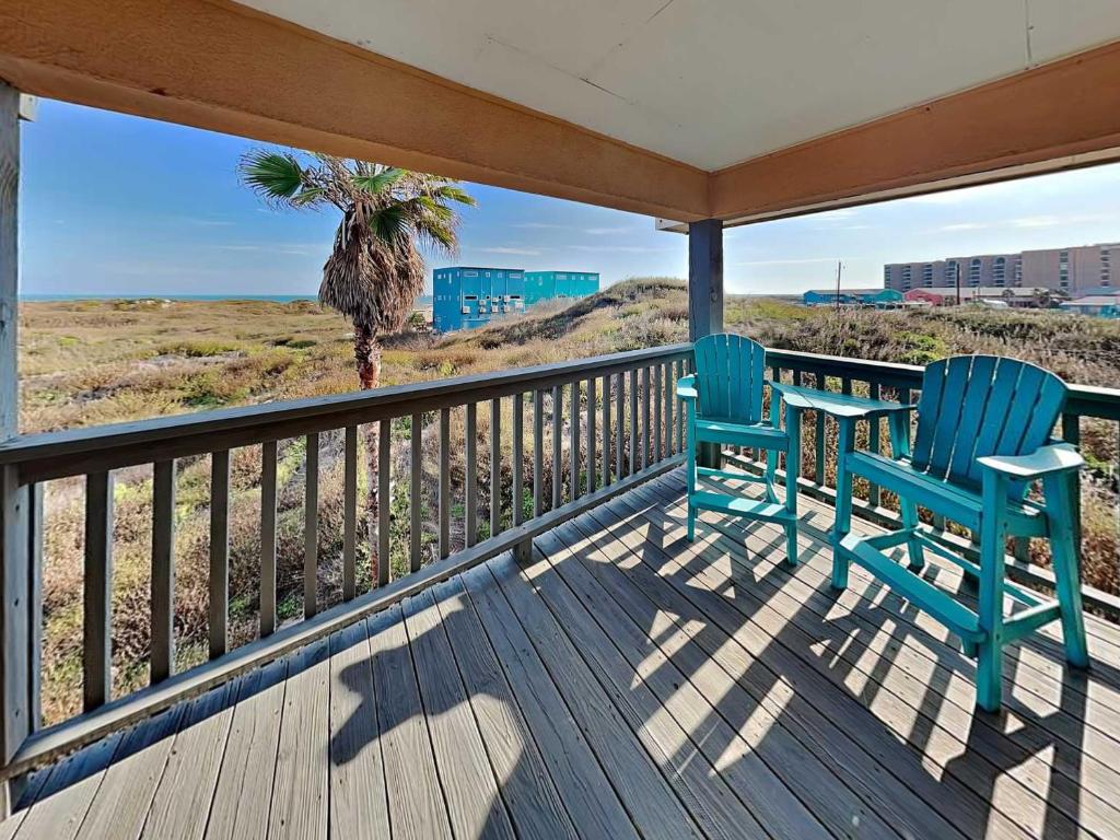 a porch with two blue chairs and a palm tree at Happy Heron in Port Aransas