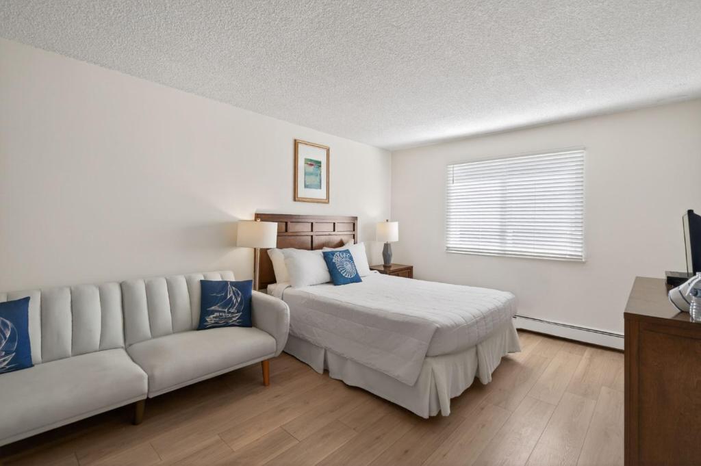 a white bedroom with a bed and a couch at Ocean Surf Resort in Montauk