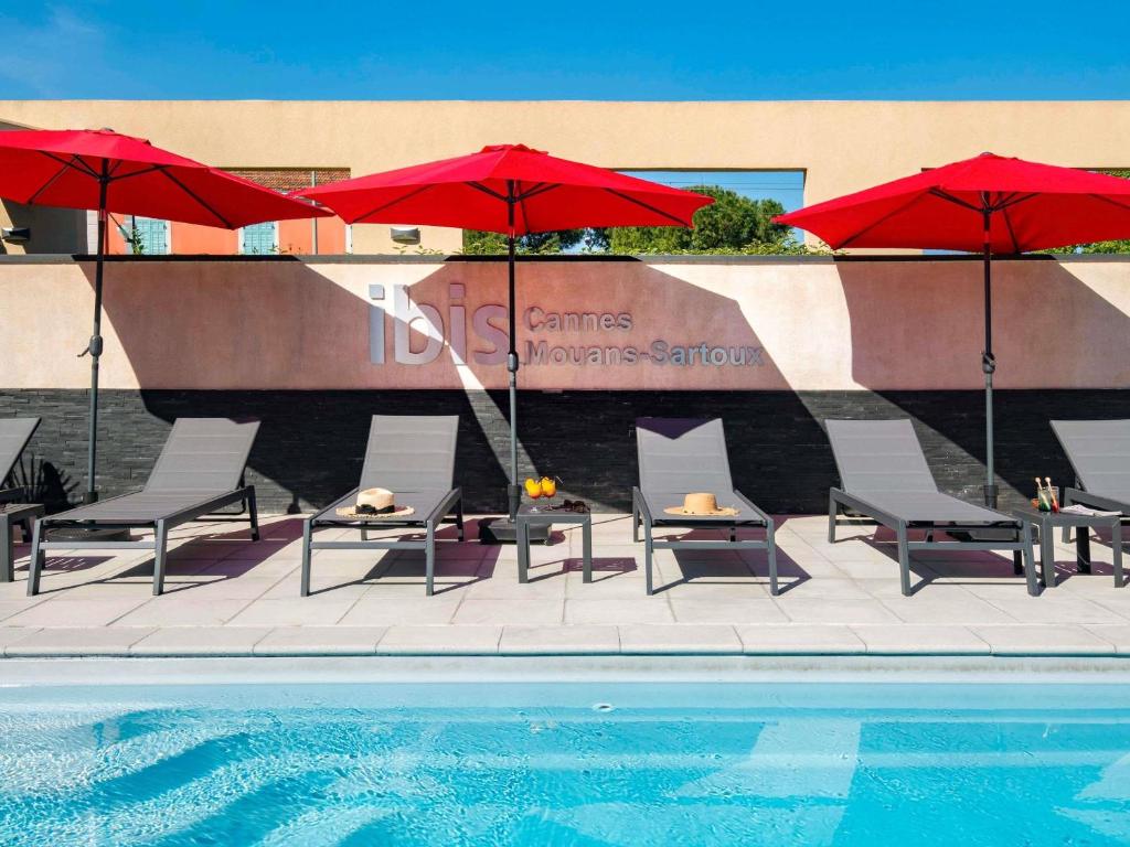 a group of chairs and umbrellas next to a pool at IBIS Cannes Mouans Sartoux Piscine parking gratuit in Mouans-Sartoux