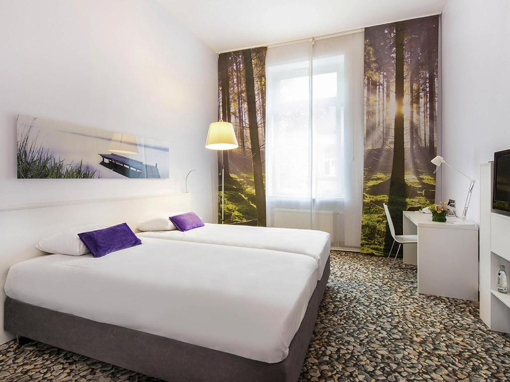 a hotel room with two beds and a tv at Ibis Styles Frankfurt City in Frankfurt