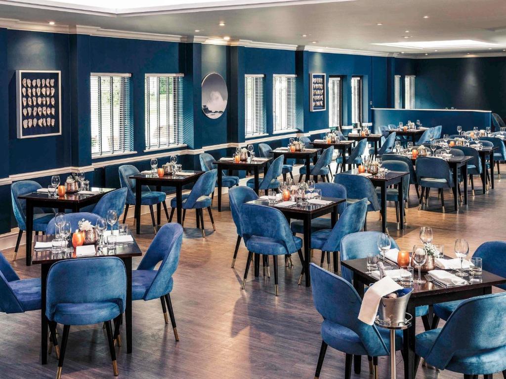 a dining room with tables and blue chairs at Mercure Swansea Hotel in Swansea