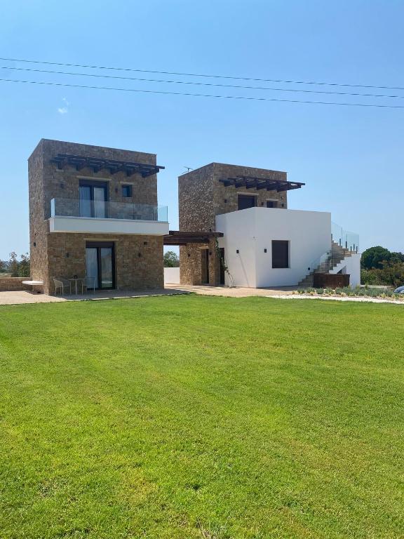 a building with a grass field in front of it at Anogeio in Afitos