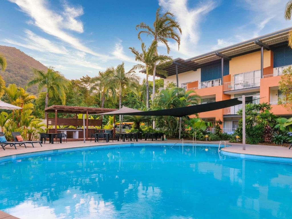 a swimming pool at a hotel with palm trees at The Sebel Palm Cove in Palm Cove