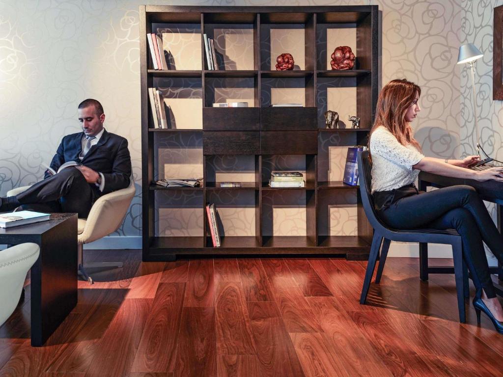 a man and a woman sitting in chairs in a room at Mercure Montevideo Punta Carretas in Montevideo