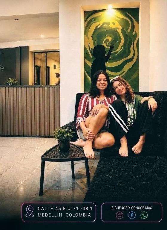 two women sitting on a couch posing for a picture at Multiverse Hostel in Medellín