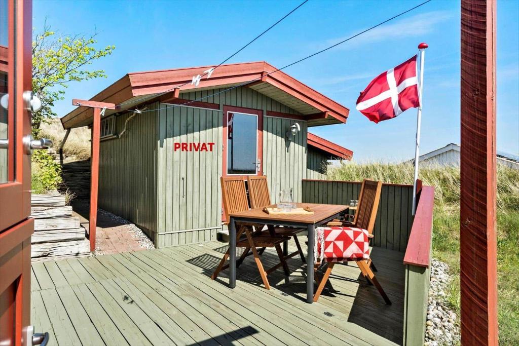 a wooden deck with a table and a flag at 4468-Hvide-Sande-Tingodden-427 in Hvide Sande