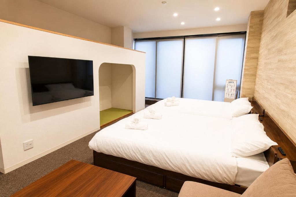 a hotel room with two beds and a flat screen tv at Tsunagu森ノ宮 in Osaka