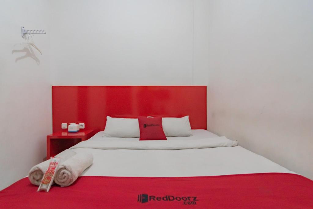 a large bed with a red headboard in a room at RedDoorz @ Galuh Mas in Karawang
