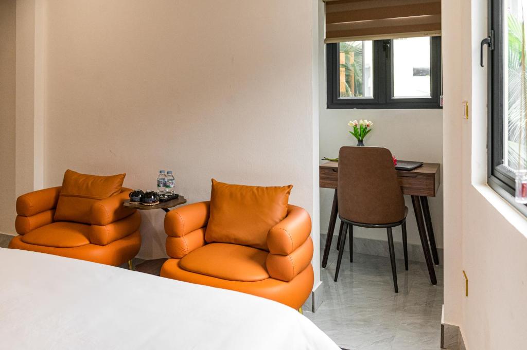 two orange chairs in a room with a table at Aura Retreat Boutique Hotel Hanoi in Hanoi