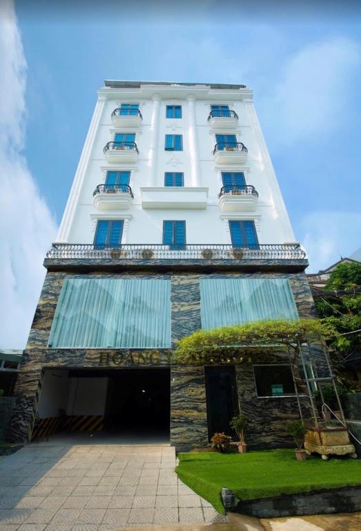 a tall white building with blue windows on it at Hoàng Long Hotel 