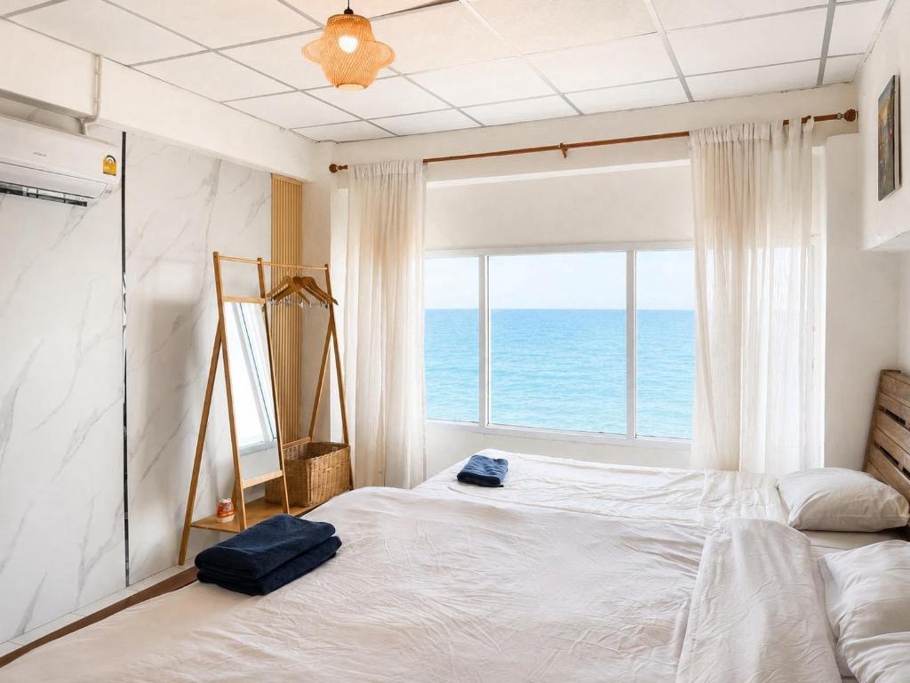 a bedroom with a large bed with a view of the ocean at Gao Check in Phala Beach Front in Rayong