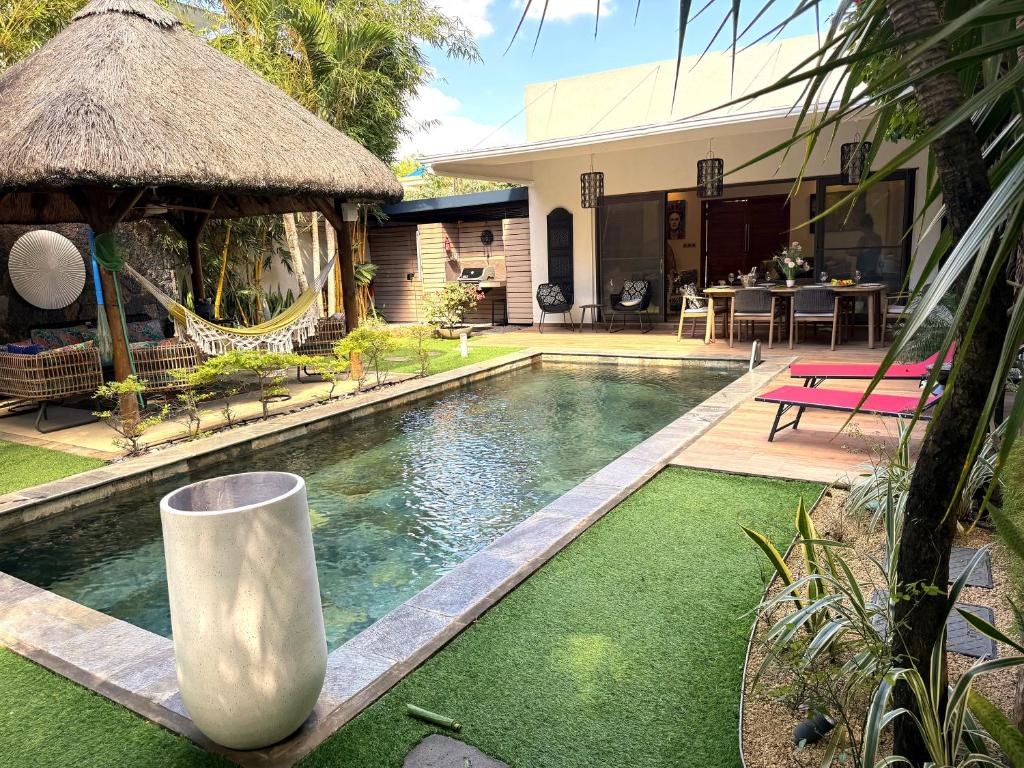 a backyard with a swimming pool and a house at ORCHID Villa luxueuse avec piscine privée- A 600m de la plage in Pereybere