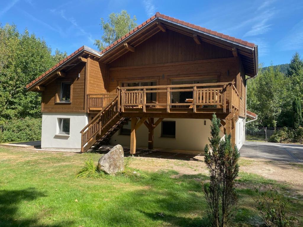 a log house with a deck on the side of it at Chalet des Épicéas - babyfoot billard & PS in Gérardmer