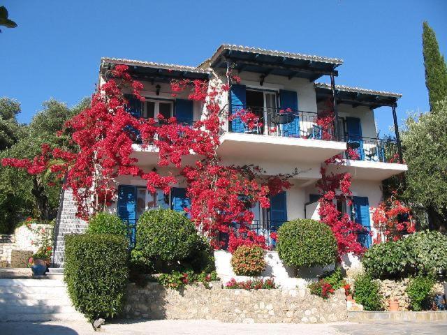 a building with red flowers on the side of it at Villa Fiorita in Paleokastritsa