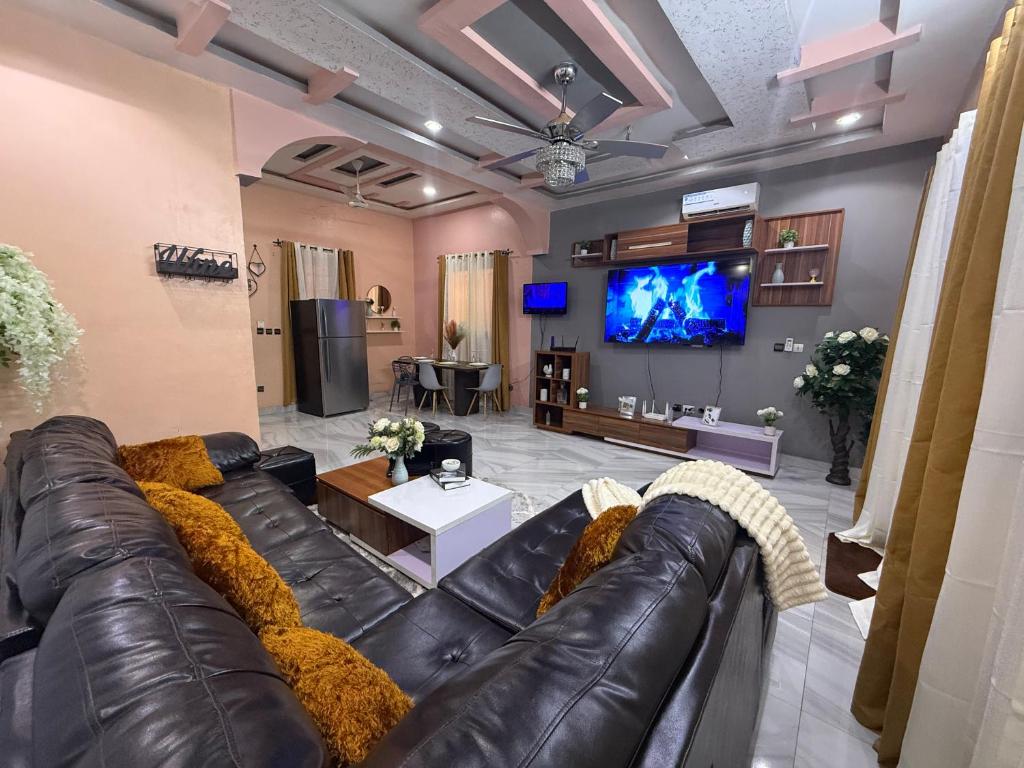 a living room with a leather couch and a tv at Royal Zam Résidence in Ouagadougou