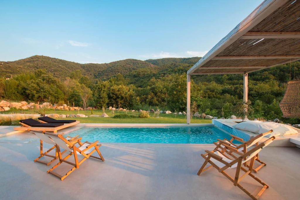a swimming pool with two lounge chairs and a table at Aristotelia Gi - Premium Luxury Villas with Private Pools in Olympiada