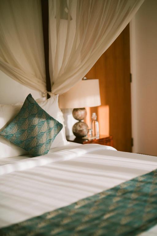 a bed with a green pillow on top of it at Akilea Villas Bali in Uluwatu