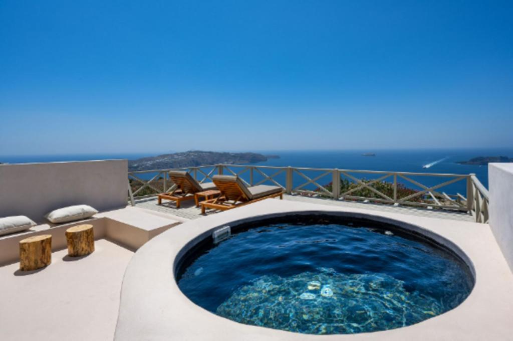 a hot tub on a patio with the ocean in the background at Santo Blue Santorini Caldera View Luxury Houses in Megalochori