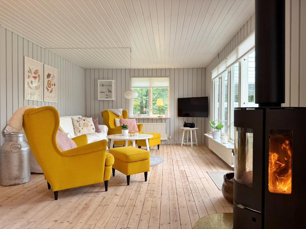 a living room with yellow chairs and a fireplace at Wonderful cottage close to lakes in Södra Rörum