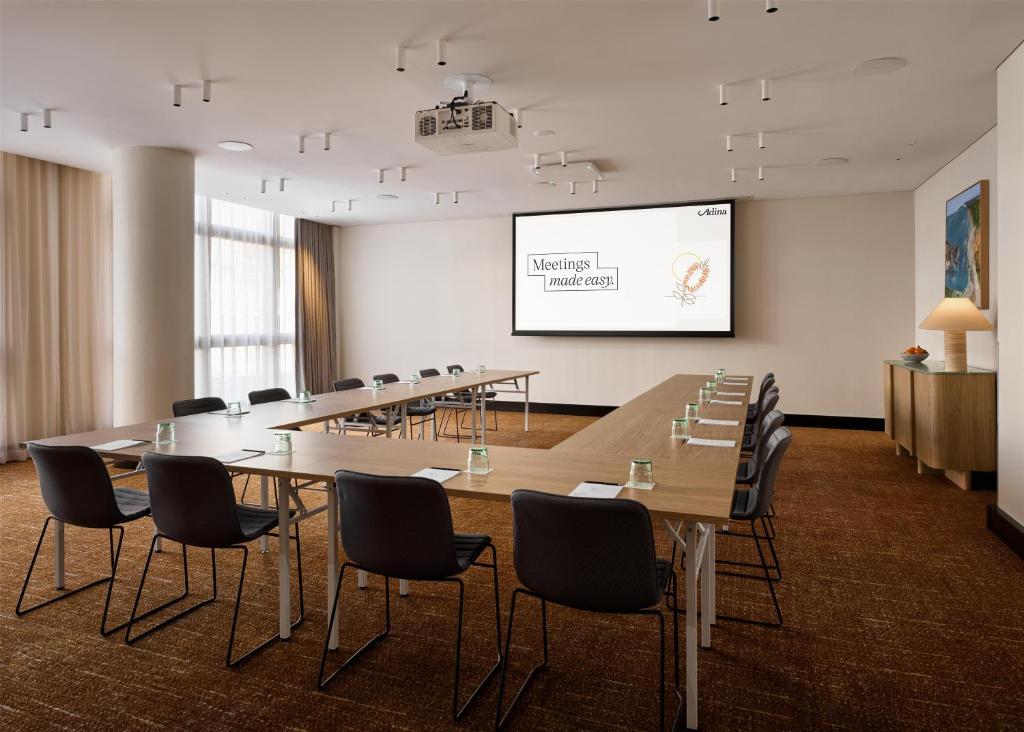 a conference room with a long table and chairs and a screen at Adina Sydney Darling Harbour in Sydney