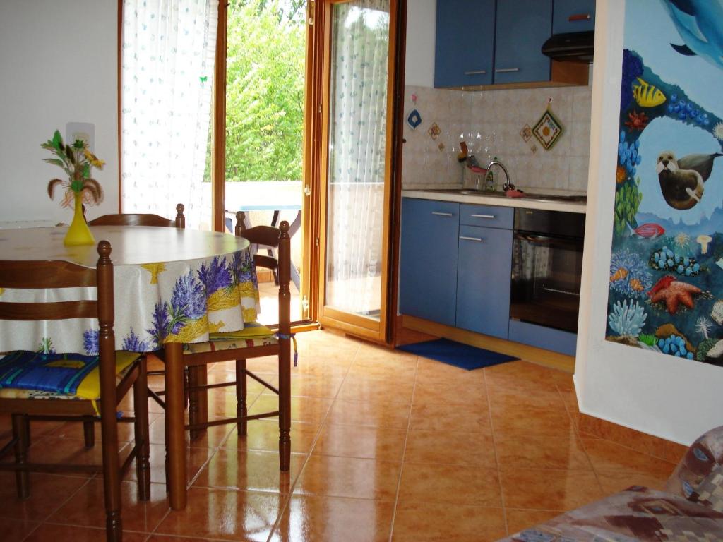 cocina con armarios azules, mesa y sillas en Apartments and Rooms Suzana, en Kršan