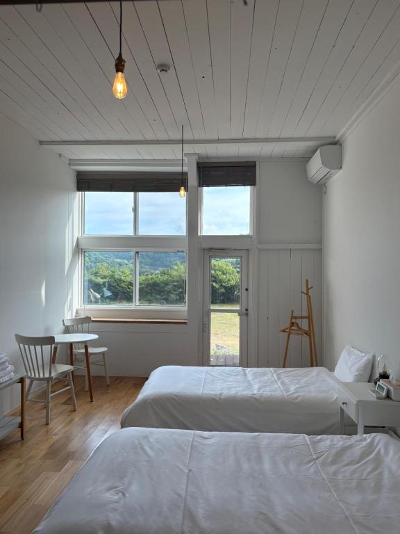 a bedroom with two beds and a table and a window at 里山のいぶき舎 in Goto