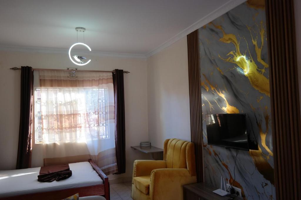 a living room with a yellow chair and a painting at Kristina Gardens 1BD & Studio Homes in Voi
