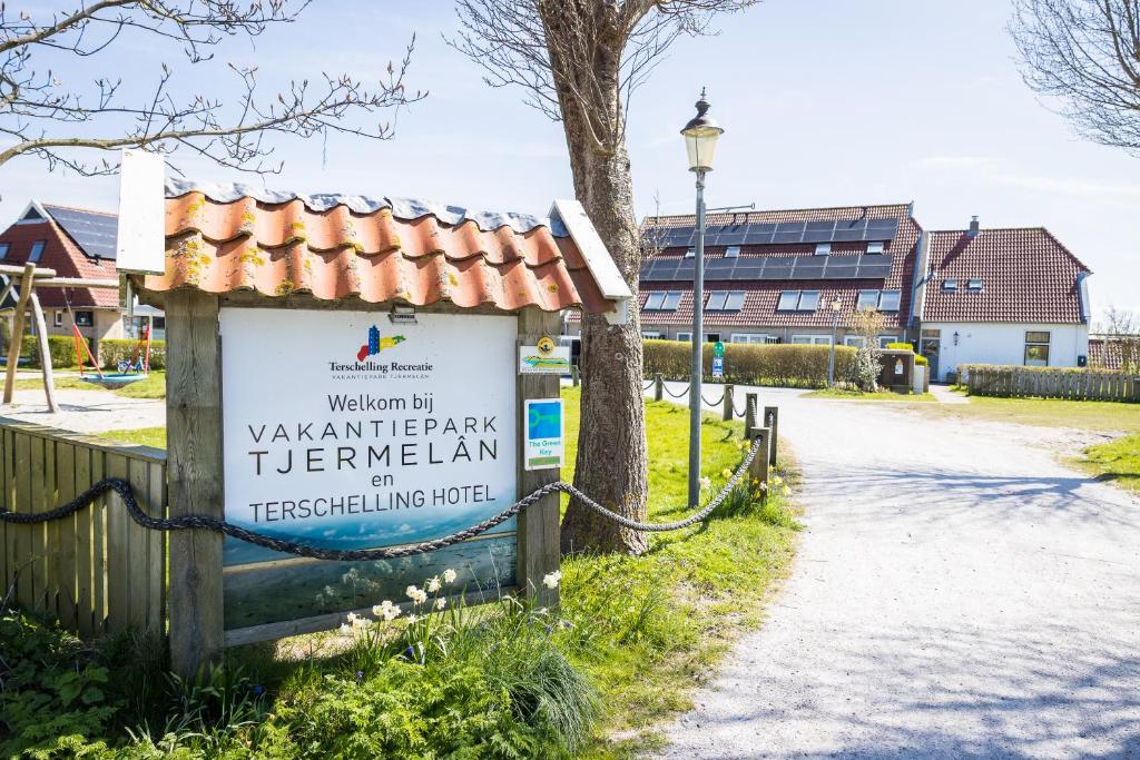 a sign for a park with a building in the background at Appartementenhotel Tjermelân Terschelling in Oosterend