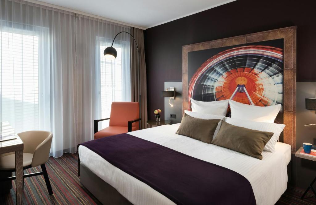 a hotel room with a bed and a desk at Leonardo Hotel Munich City South in Munich