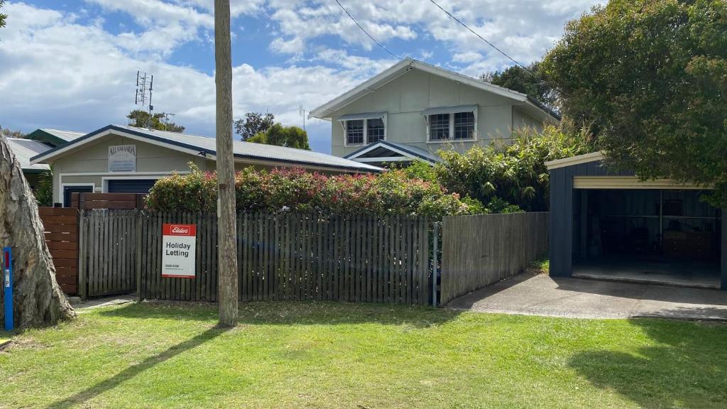 a fence in front of a house with a garage at Allamanda House, 3 Willow Street in Crescent Head