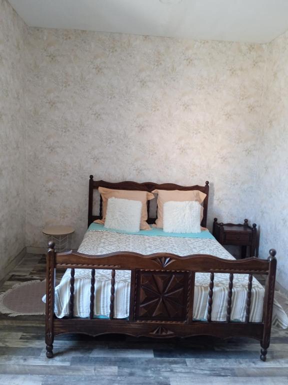 a bedroom with a wooden bed with pillows at Joli hébergement indépendant in Lavelanet